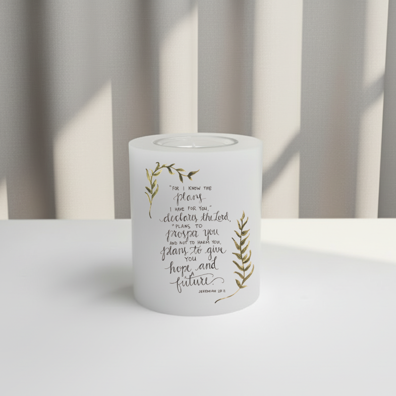 White everlasting candle with text and leaf designs on a white surface.