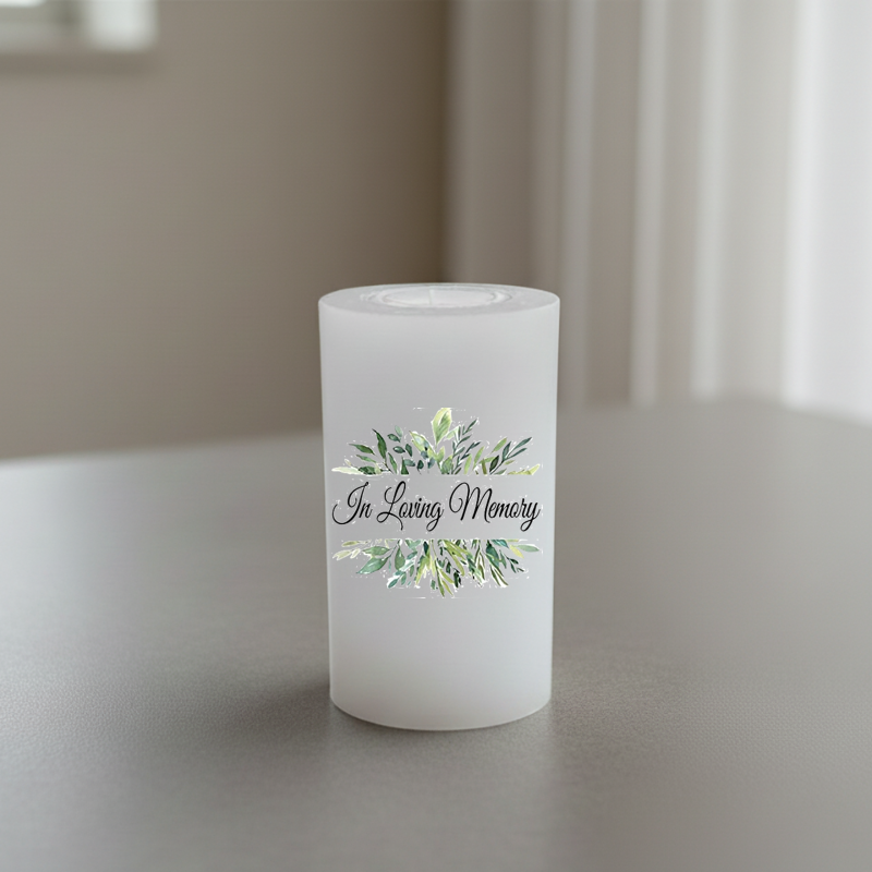 A white candle with the words 'In Loving Memory' and a green watercolor floral wreath design.