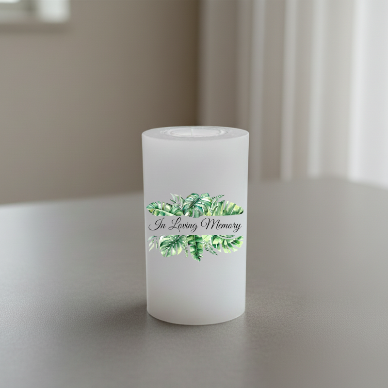 White memory candle printed with green leaves and text