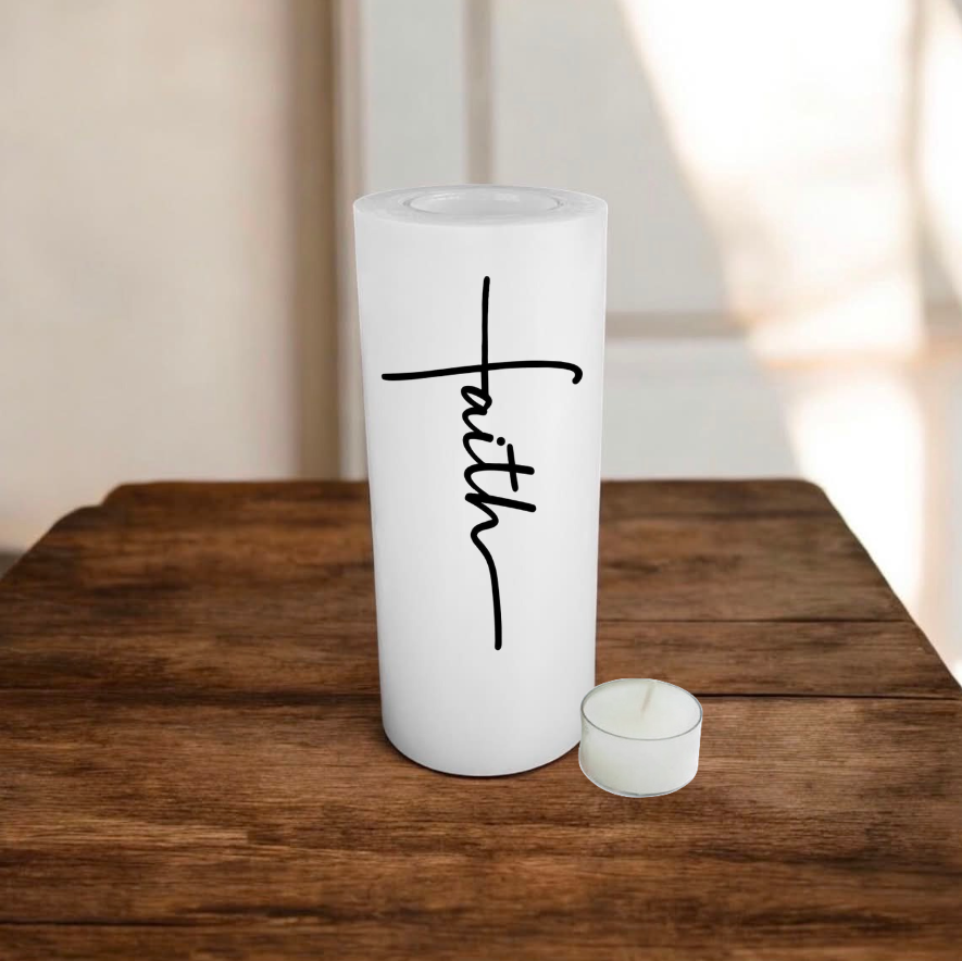 White candle with text 'faith', placed on a wooden surface.