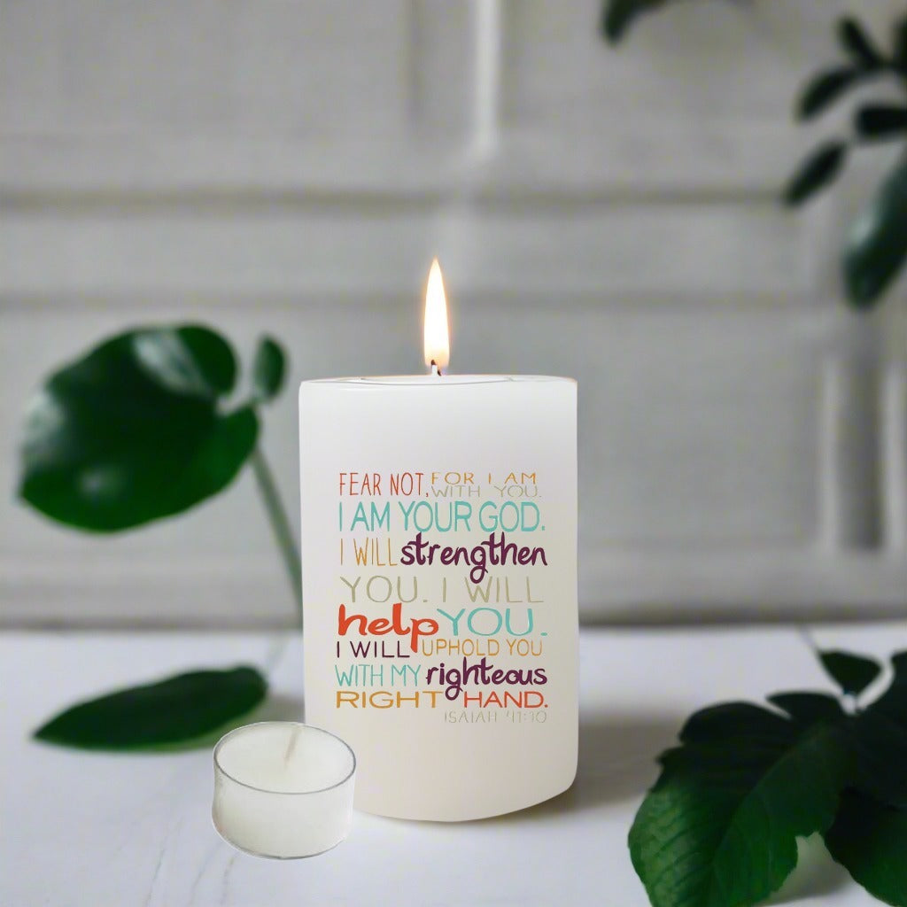 Candle with motivational text on a white surface with green leaves in the background