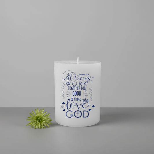 White candle with blue text and a green flower on a grey background