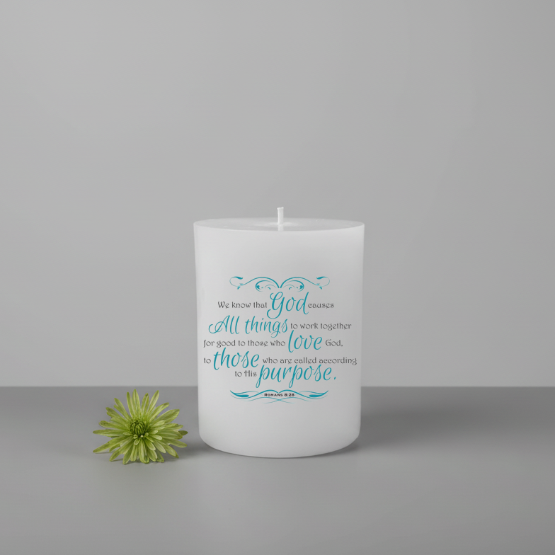 White candle with blue text and a green flower on a gray background