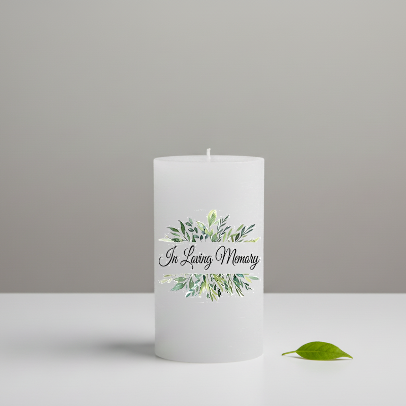 A white candle with the words 'In Loving Memory' and a green watercolor floral wreath design.