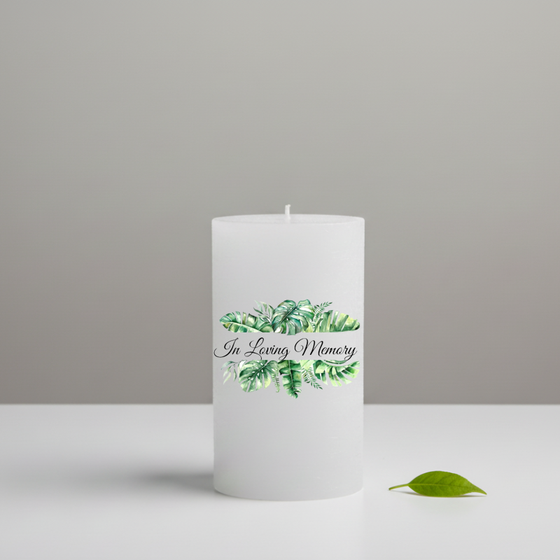 White memory candle printed with green leaves and text