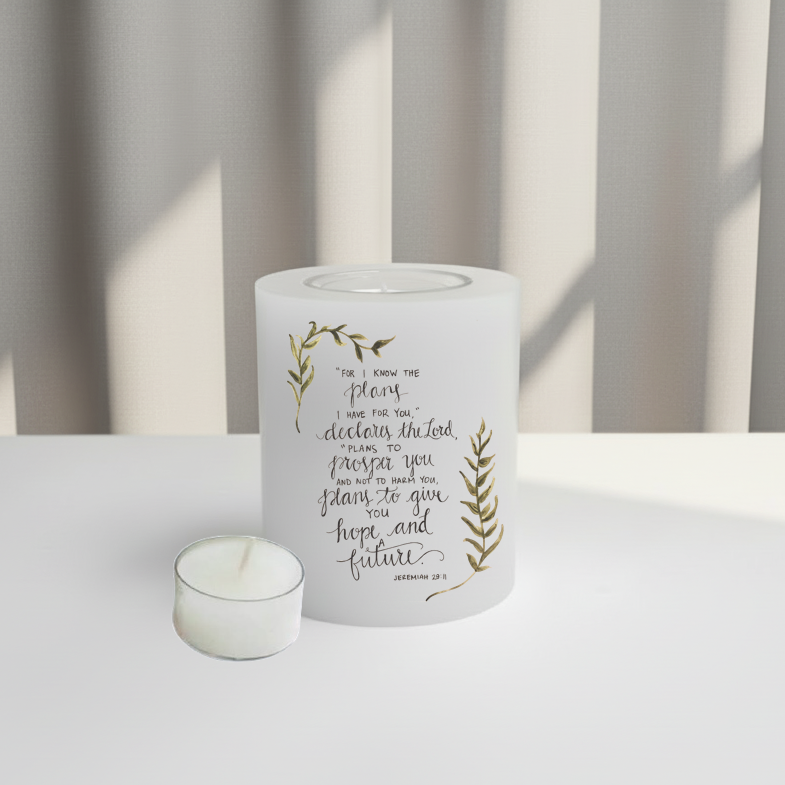 White everlasting candle with text and leaf designs on a white surface.