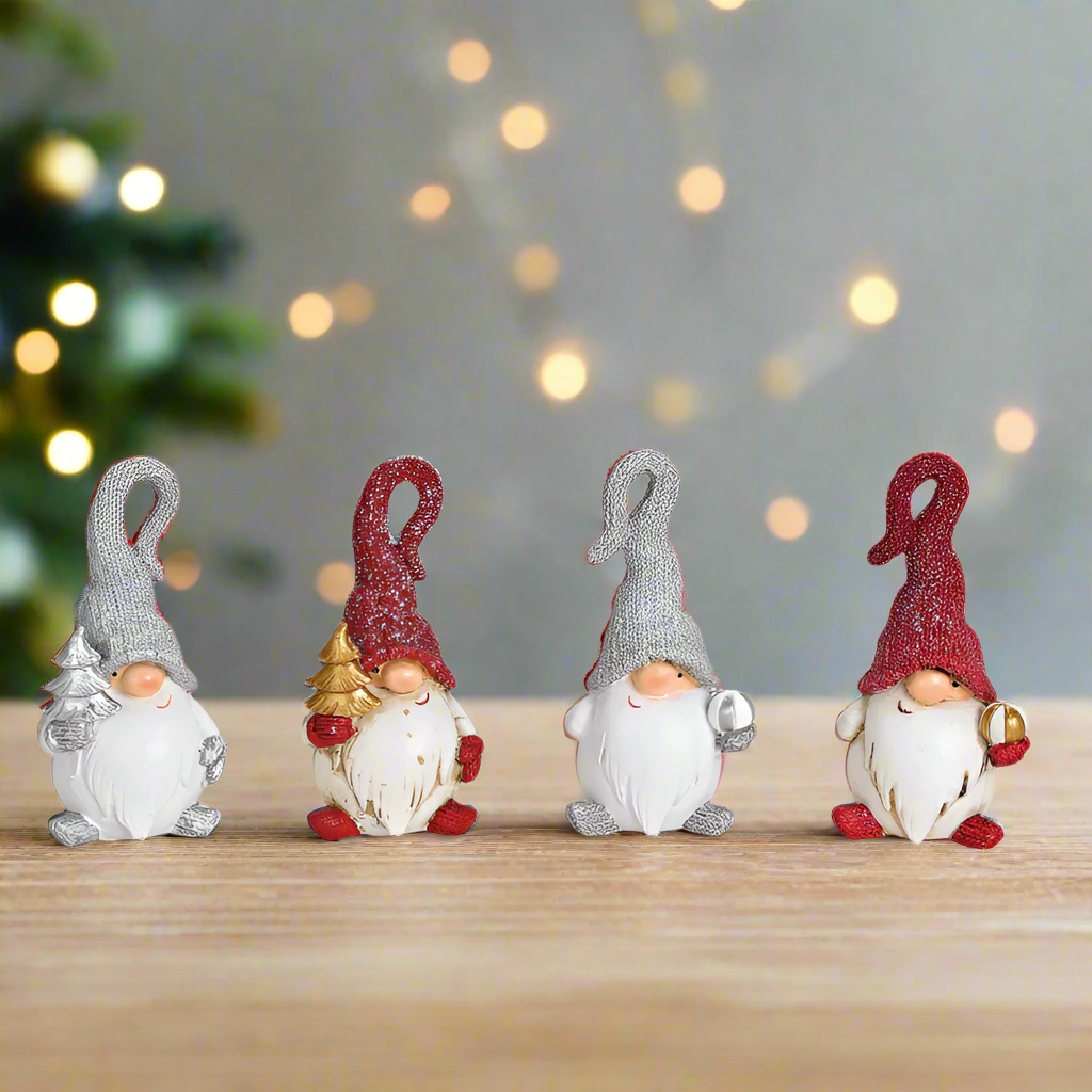 Four small gnome figurines with red and gray pointed hats on a white background