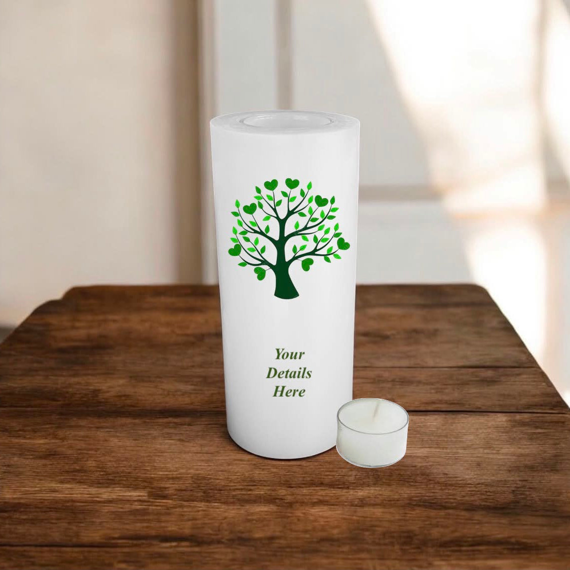 White candle with a green tree design on a wooden surface