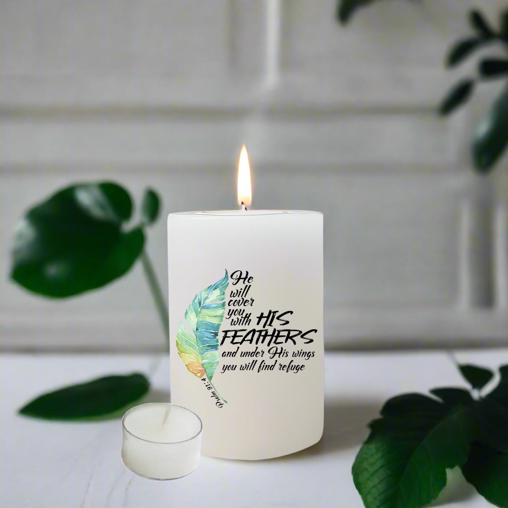 A white candle with a teal and yellow feather graphic and the printed quote 'He will cover you with His feathers and under His wings you will find refuge' and green leaves around it.