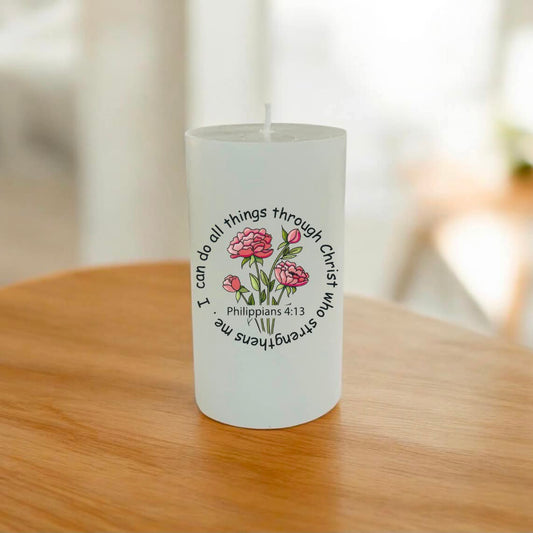 A white candle with a printed graphic of pink flowers and the text 'I can do all things through Christ who strengthens me Philippians 4:13'
