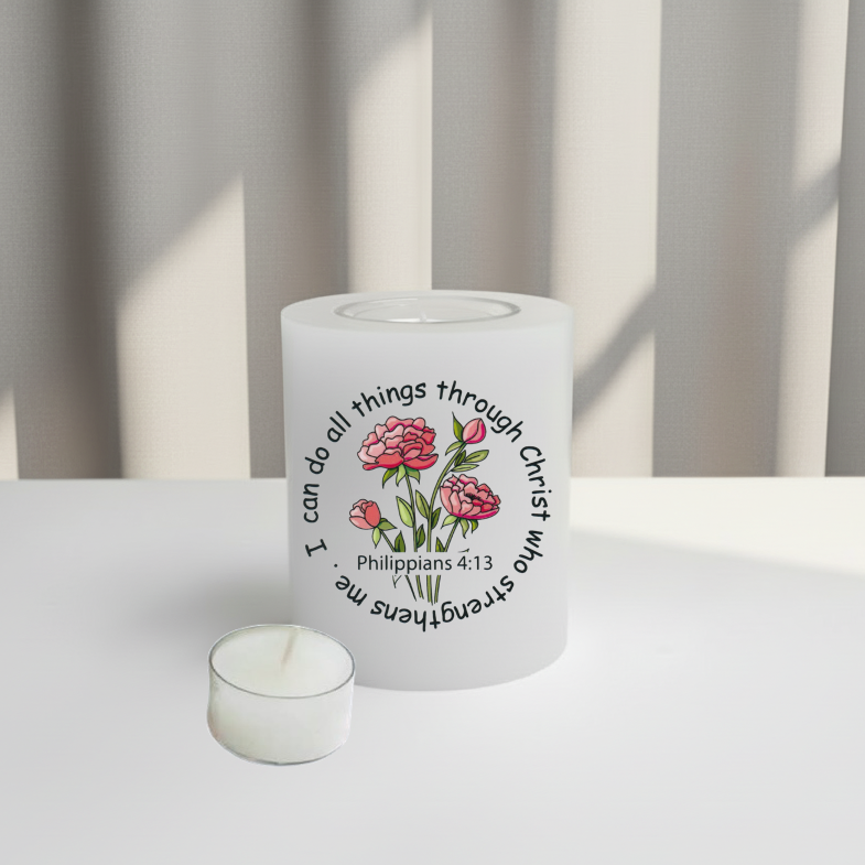 A white candle with a printed graphic of pink flowers and the text 'I can do all things through Christ who strengthens me Philippians 4:13' in black.