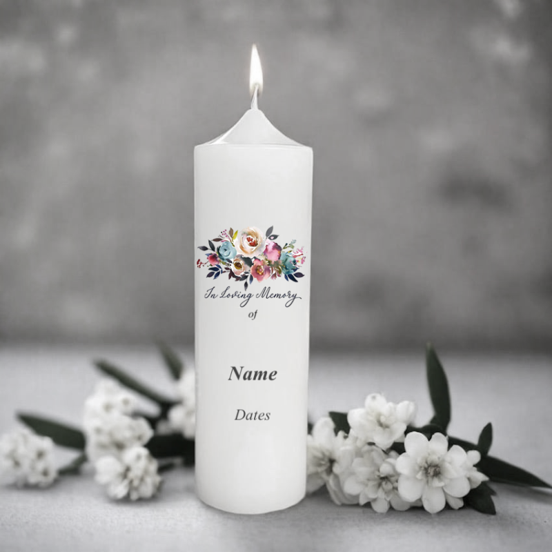 White memorial candle with floral design and text on a gray background