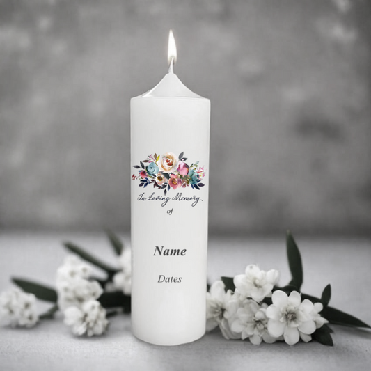 White memorial candle with floral design and text on a gray background