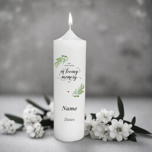 White memory candle with 'In Loving Memory' text and floral design on a gray background with white flowers.