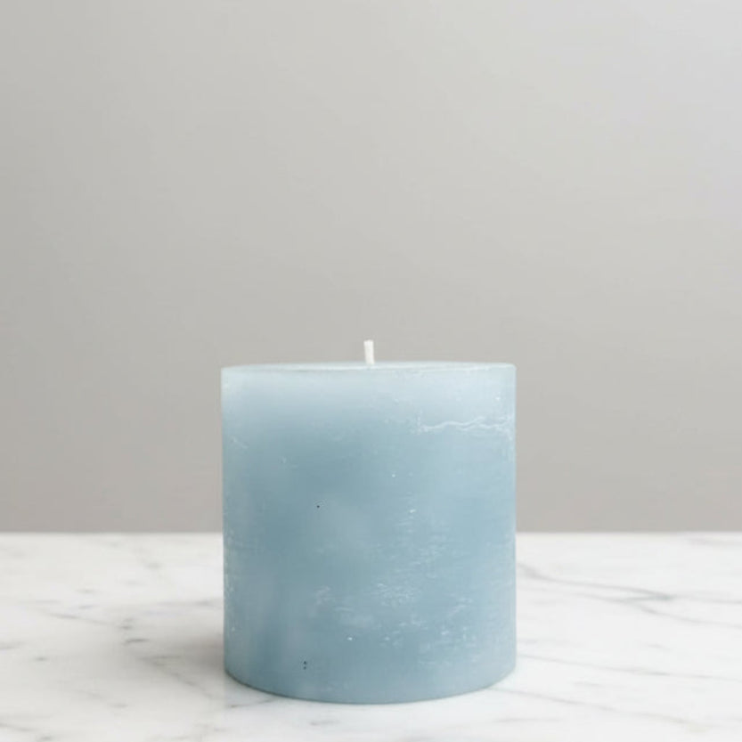 Light blue candle on a marble surface with a neutral background