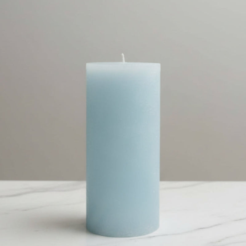 light blue candle on a surface with a neutral background