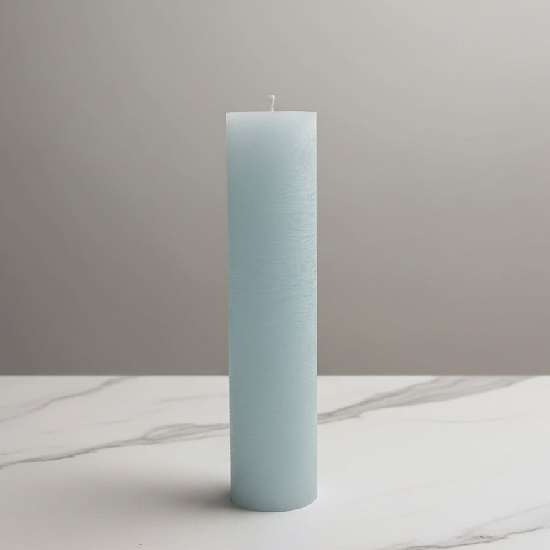 Light blue cylindrical candle on a white surface with a neutral background