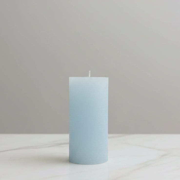 Light blue candle on a white surface with a neutral background