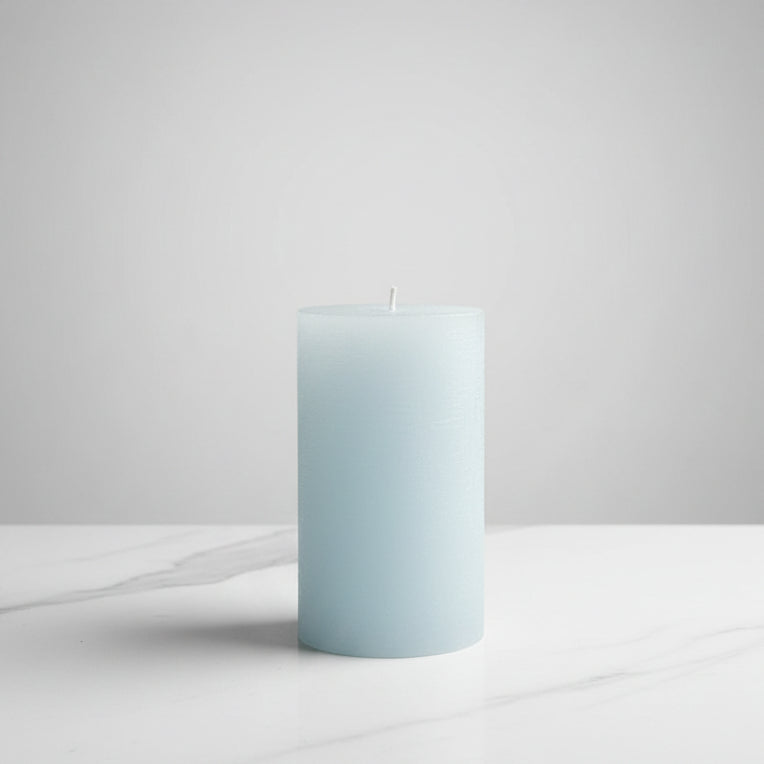 Light blue candle on a white surface with a neutral background