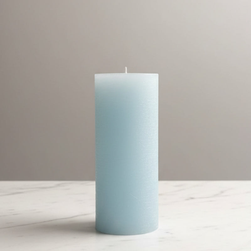 Light blue candle on a white surface with a neutral background