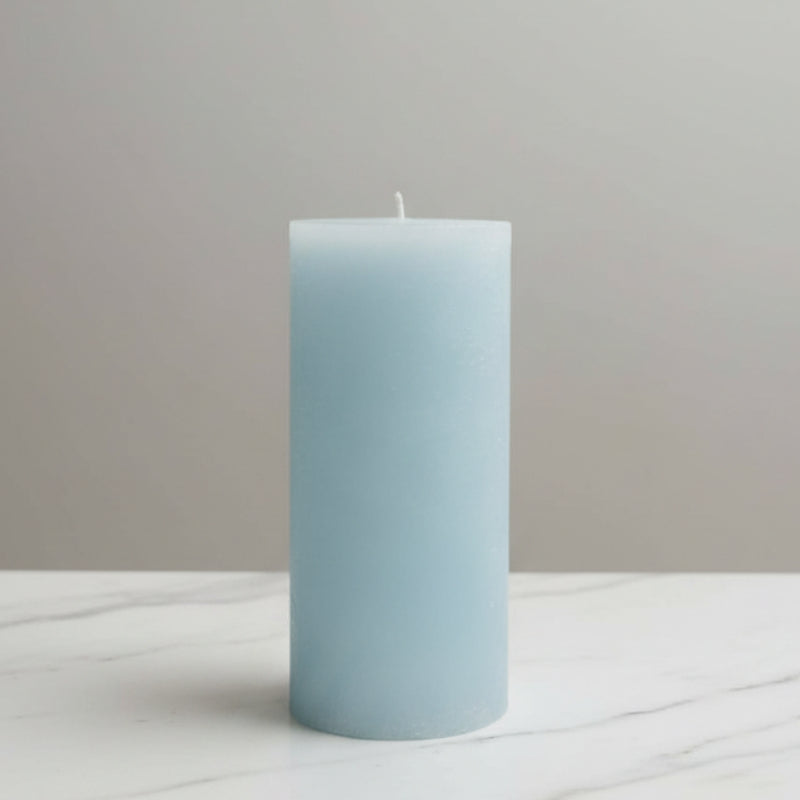Light blue candle on a white surface with a neutral background
