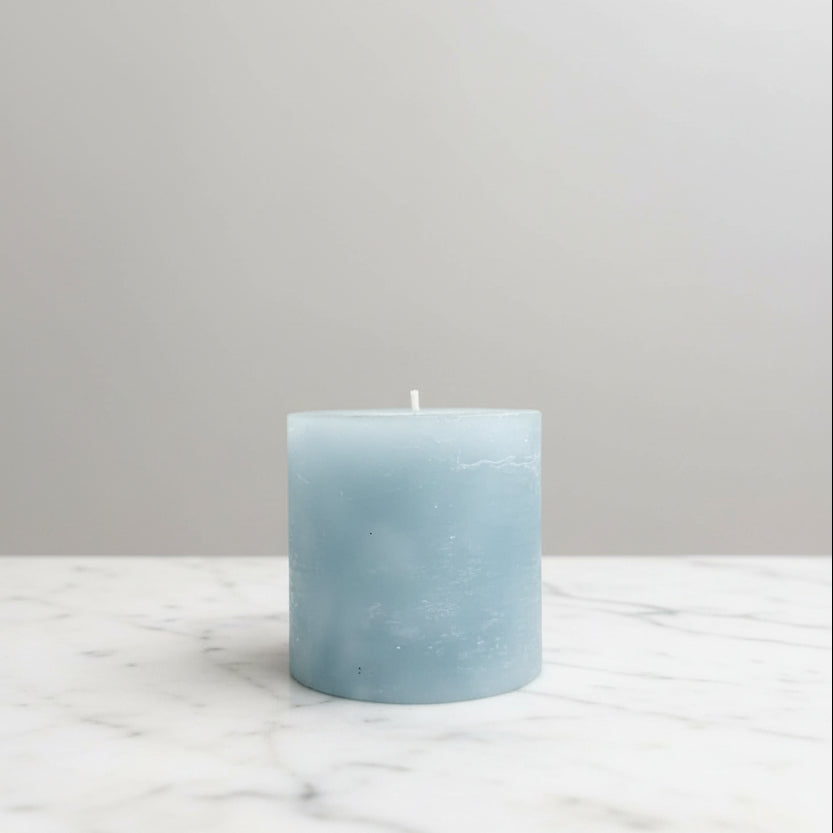 Blue candle on a white surface with a neutral background