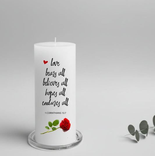 A white pillar candle with a text and a rose, placed on a glass plate holder
