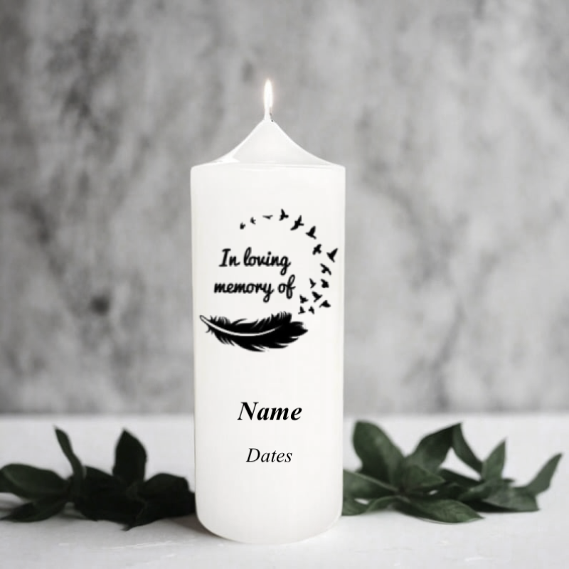 White memorial candle with 'In loving memory' text and feather design on a gray background