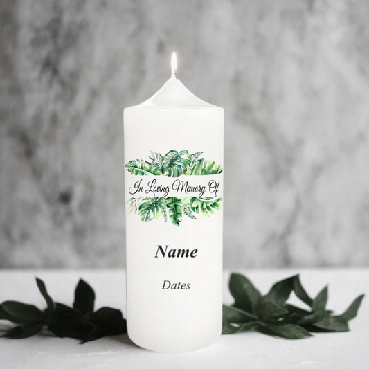 White memory candle with green leaf design and text on a grey background