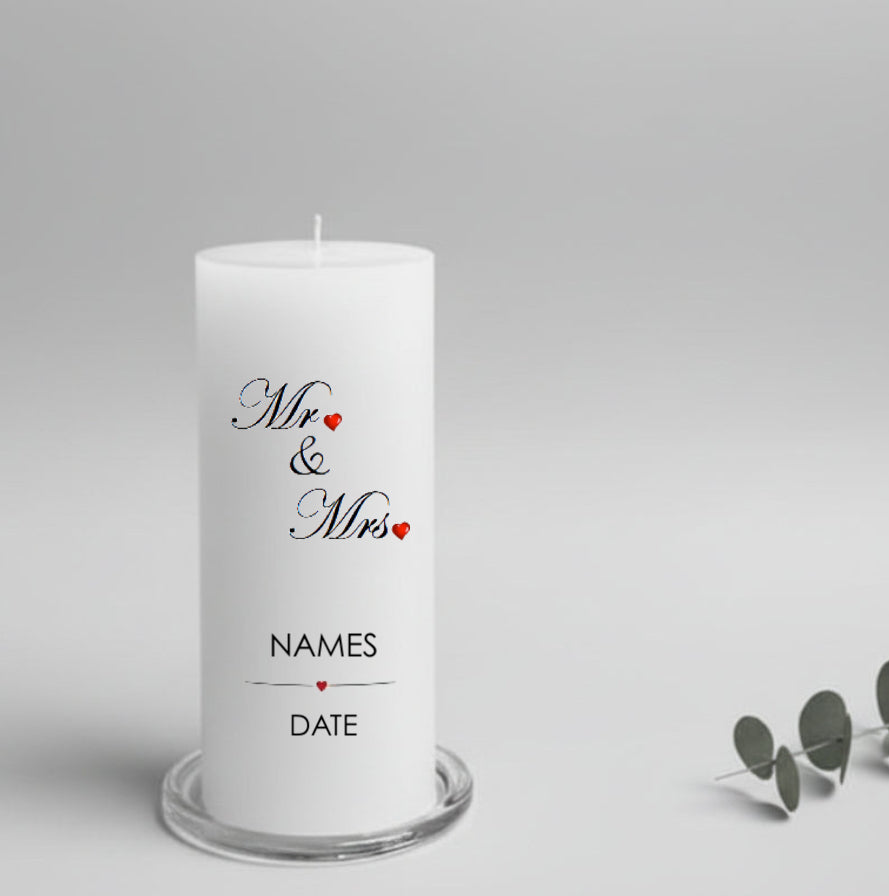 A white cylindrical candle printed with the words 'Mr & Mrs' in black script with small red hearts, plus 'NAMES' and 'DATE' below.