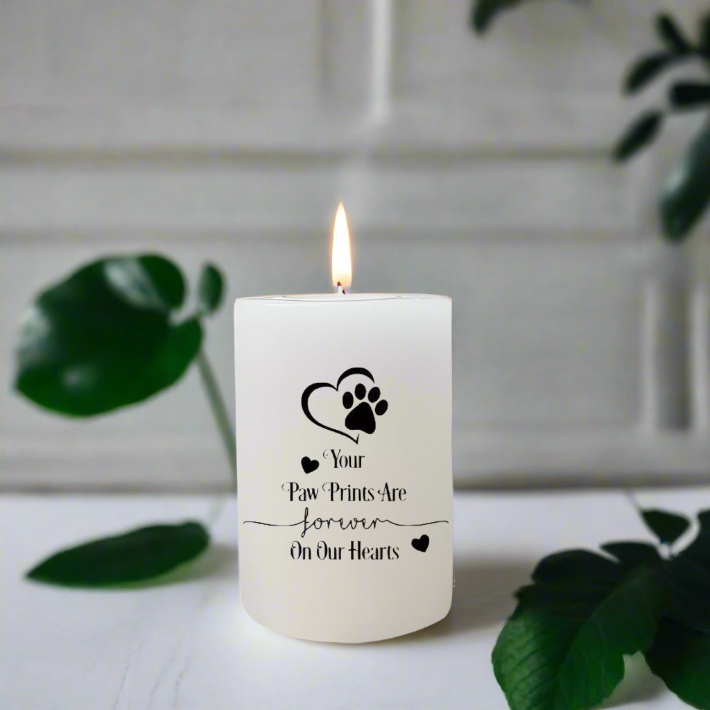 White candle with a text on a white surface with green leaves.