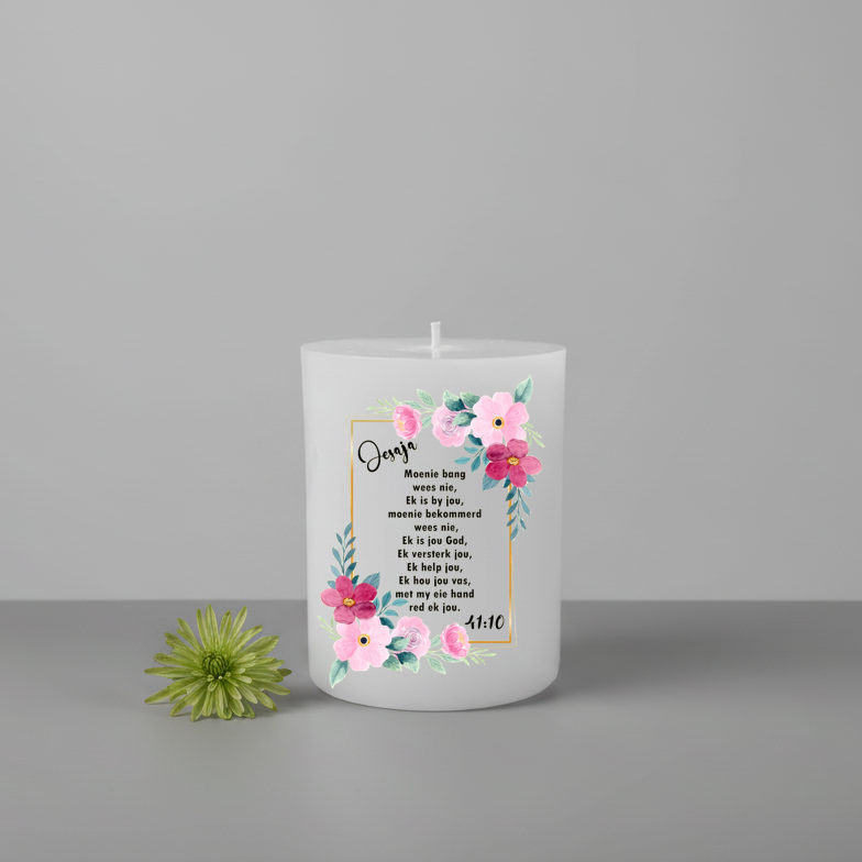 White candle with floral design and Afrikaans text on a grey background