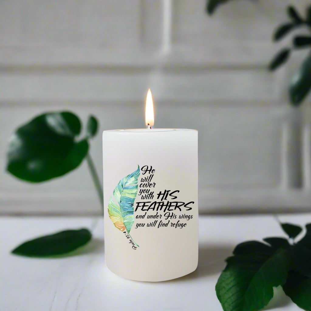 Candle with feather design and text on a white surface with green leaves.