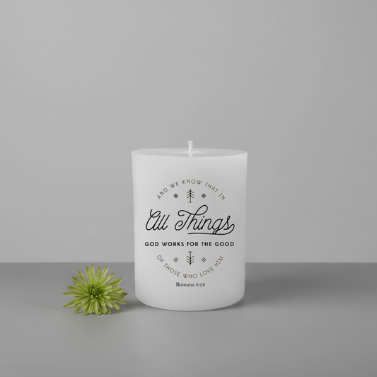 White candle with text and a green flower on a gray background