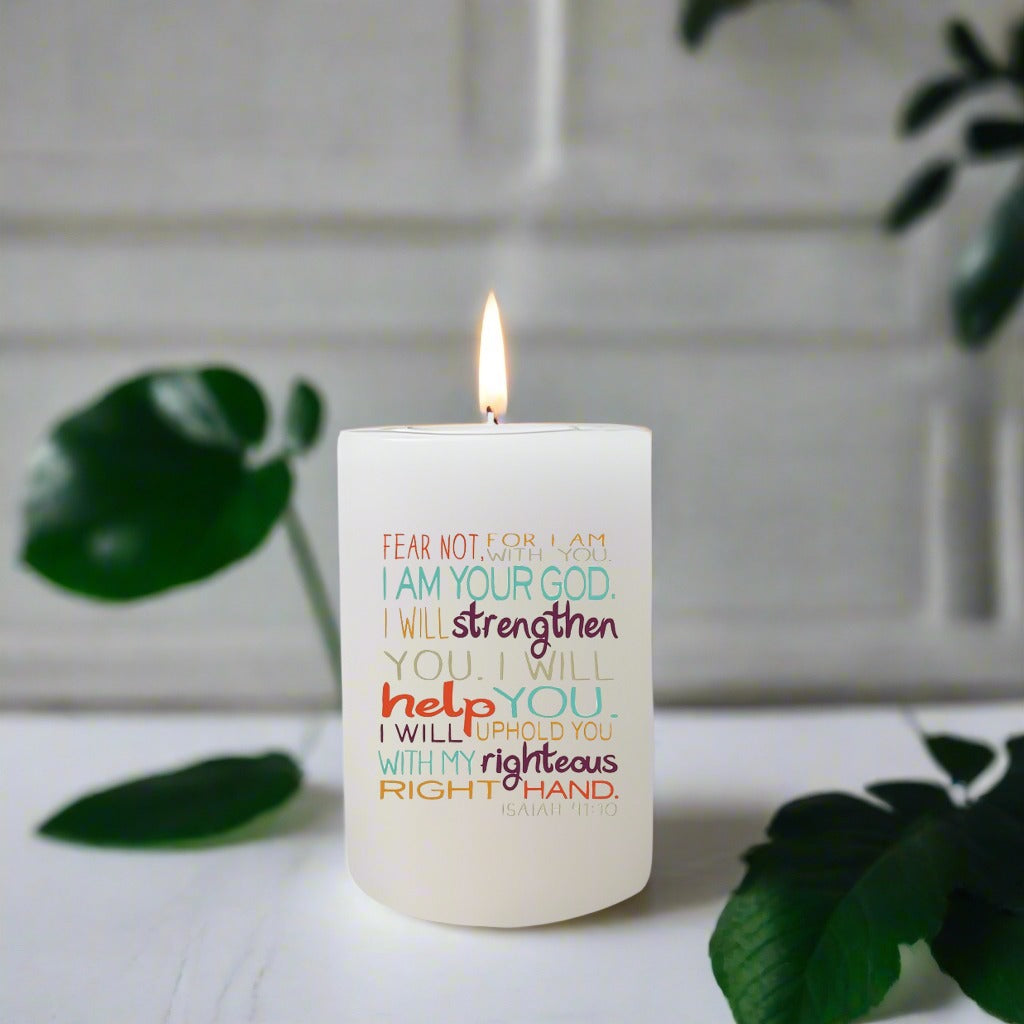 Candle with motivational text on a white surface with green leaves in the background