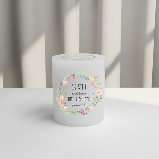 White candle with floral design and text on a white surface.