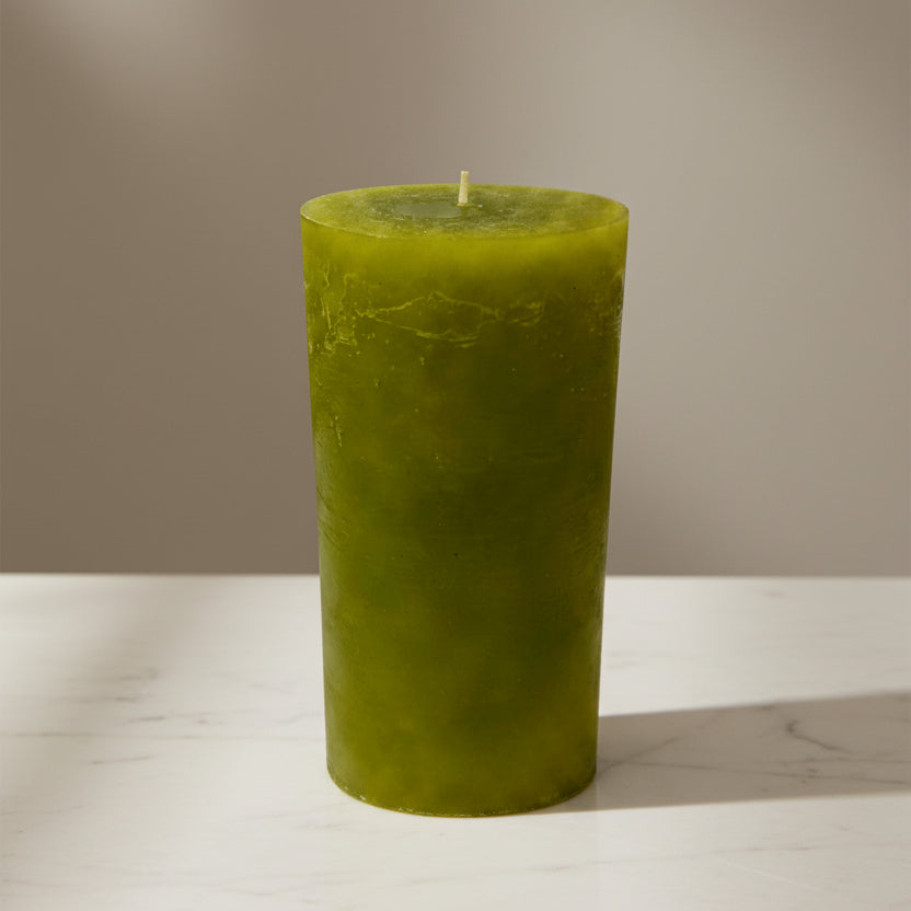Green candle on a surface and a neutral background