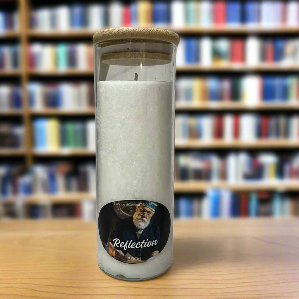 Scented Denga Candle in a glass jar with a wooden lid on a wooden surface, featuring a label with a face and the word 'Reflection'.