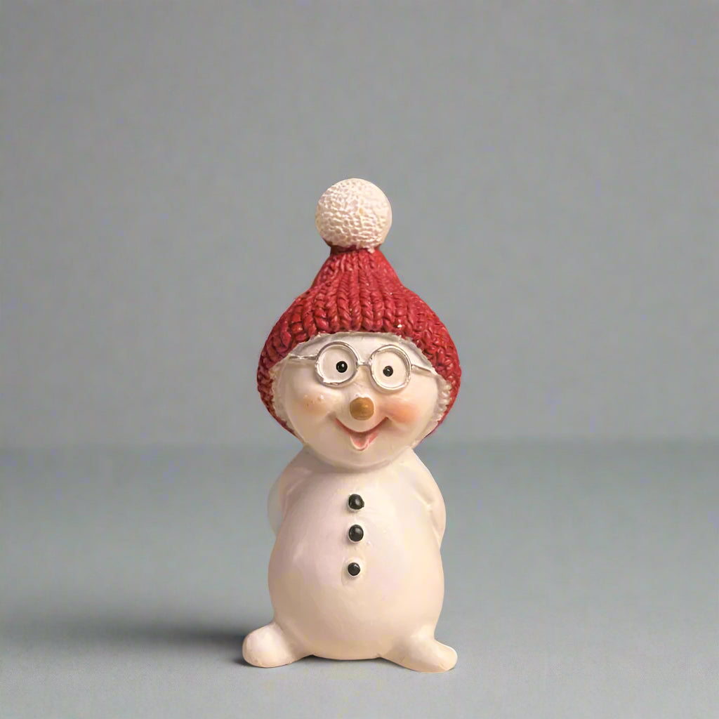 Snowman figurine with a red knit beanie and glasses on a neutral background