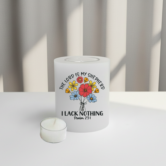 A white candle with a colourful floral graphic and the text 'THE LORD IS MY SHEPHERD I LACK NOTHING Psalm 23:1' printed on the front, set on a white surface.