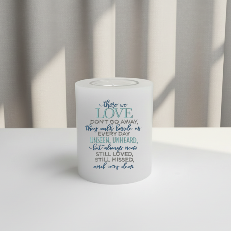 White memorial candle with text on a white surface and striped curtain background