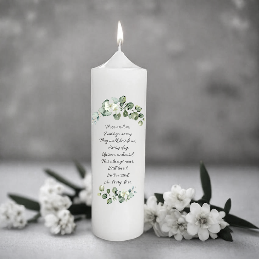 White memory candle with floral design and text on a gray background