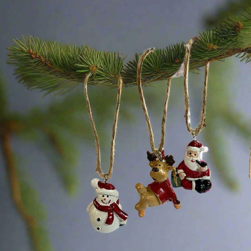 Three Christmas-themed ornaments on a fir branch