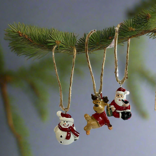 Three Christmas-themed ornaments on a fir branch