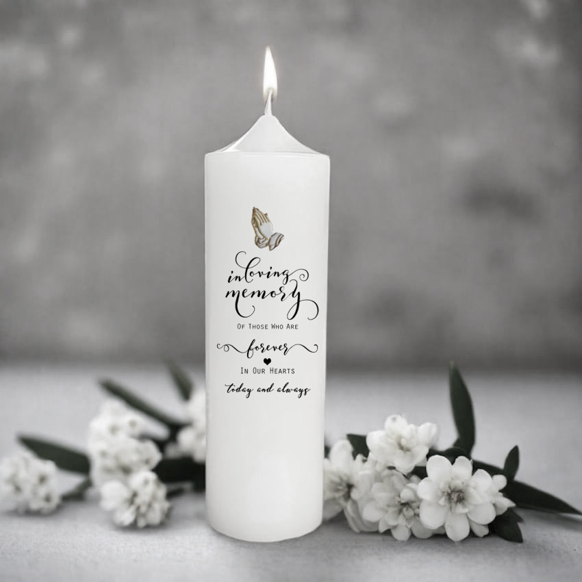White memory candle with text and butterfly design on a gray background with flowers