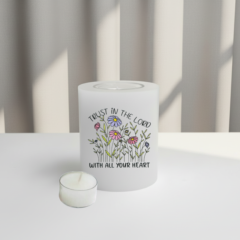 A white candle with a built-in glass holder to place a tealight. Designed with printed flowers and text
