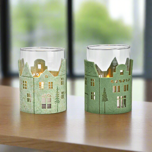 Two green candle holders shaped like houses on a white background