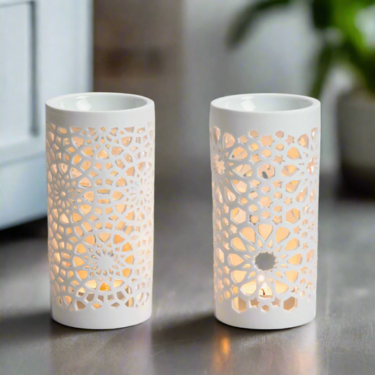 Two white ceramic fragrance burner lamps with intricate cut-out designs in a living room.