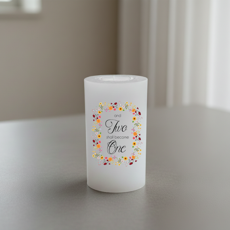 A white candle with a floral wreath design and the text 'and Two shall become One' in black script.