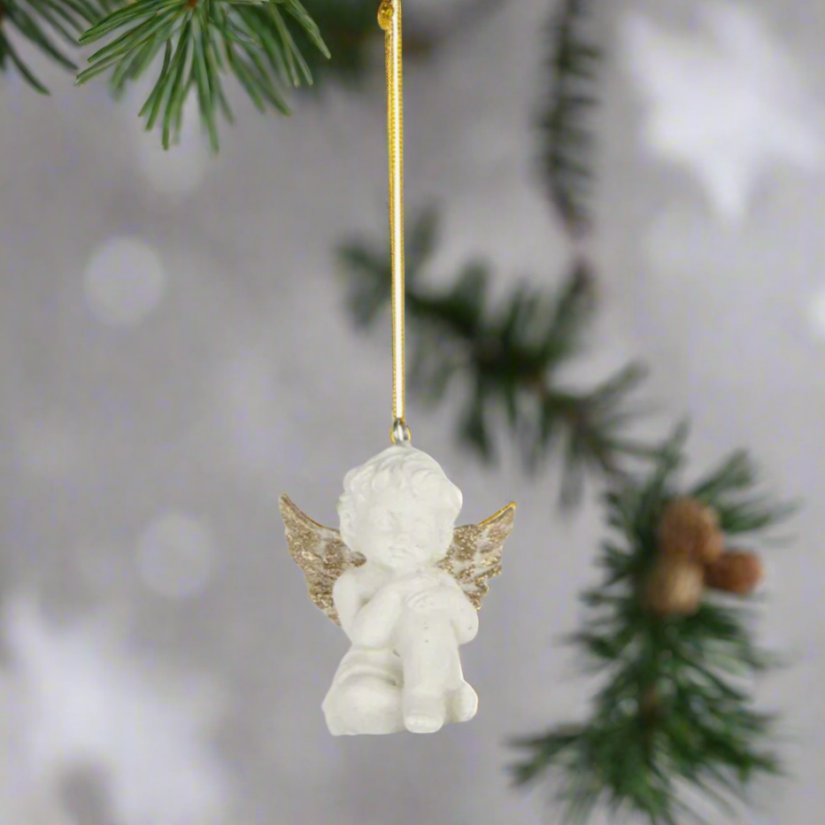 White angel figurine with gold wings on a fir branch